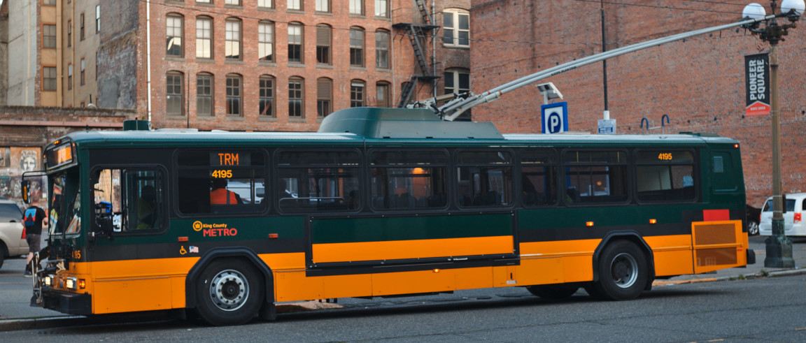 A photo of a trolley bus without a busy roof and poles midway the length of the bus